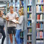 Drei studierende im Gespräch in der Universitätsbibliothek